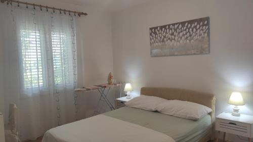 a bedroom with a bed and two lamps and a window at Apartman Iva in Kaštela