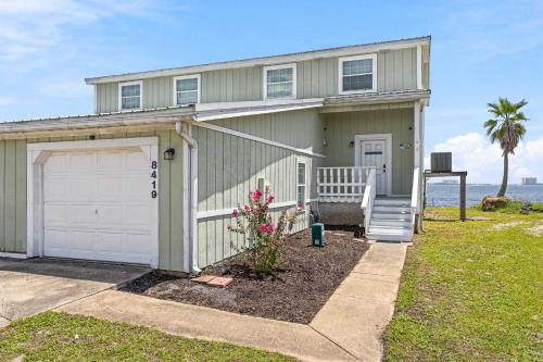 a green house with a garage and a palm tree at Waterfront Views & Beach Access - pet friendly in Navarre