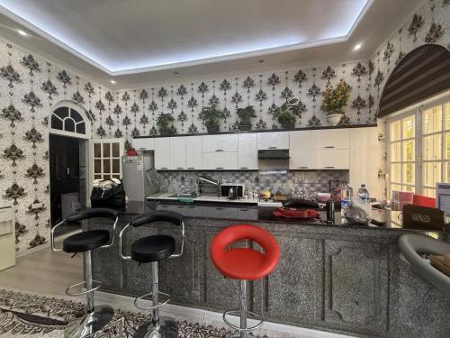 a kitchen with white cabinets and a red stool at Dacha by Bex Sueno in Samarkand