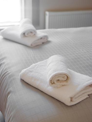 two towels are sitting on top of a bed at East Bridge House in Enniskillen