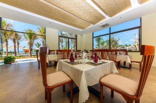 a dining room with tables and chairs and large windows at Amarin Resort & Spa Phu Quoc in Phu Quoc