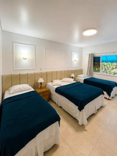 a bedroom with three beds and a window at Regine's Hotel in Itaquatiara