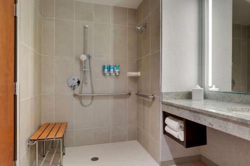 a bathroom with a shower with a bench next to a sink at Drury Plaza Hotel Cincinnati Florence in Florence