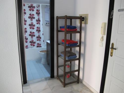 a bathroom with a toilet and a shelf with towels at Apt in Playa den Bossa next Ushuaia, beachfront, reliable host in Ibiza Town