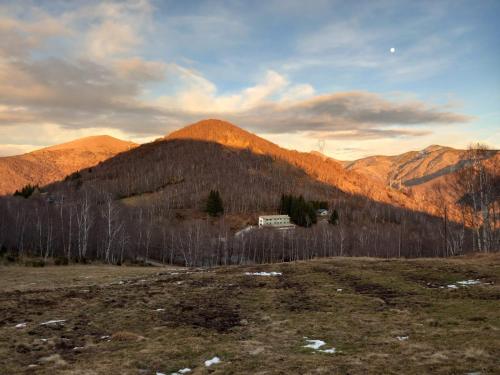 a house in a field with mountains in the background at Foresteria del Passo Forcora in Maccagno Superiore