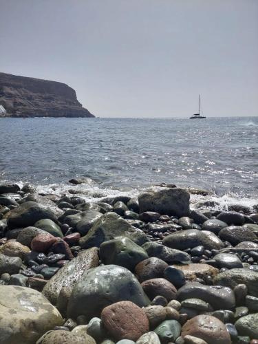 a rocky beach with a boat in the water at Playa de Mogán in Playa del Cura