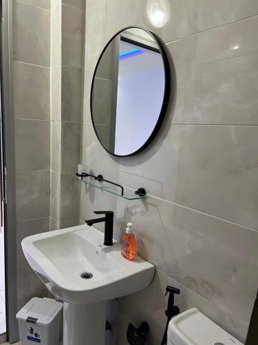 a bathroom with a sink and a mirror and a toilet at Résidence SG2 in Thiès