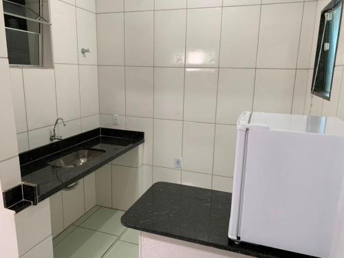a white tiled bathroom with a sink and a mirror at Pousada Brisa dos Mares Macaé in Macaé