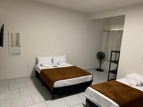 a hotel room with two beds and a fan at Pousada Brisa dos Mares Macaé in Macaé