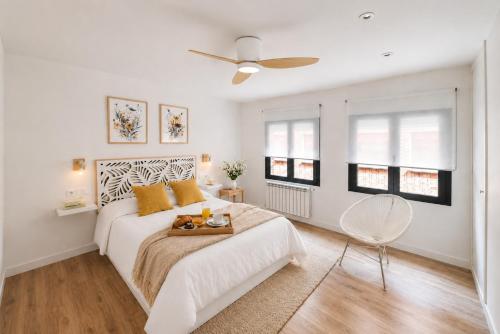 a white bedroom with a bed and a ceiling fan at Apartamento Premium Ávila PLAZA MAYOR con PARKING in Ávila