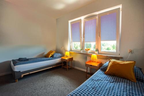 two beds in a room with two windows at Dom na Folwarku POKOJE I APARTAMENTY, BEZPŁATNY ZAMYKANY PARKING NA TERENIE POSESJI in Kielce