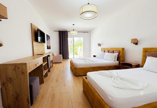 a hotel room with two beds and a television at Grecia's Dhermi in Dhërmi