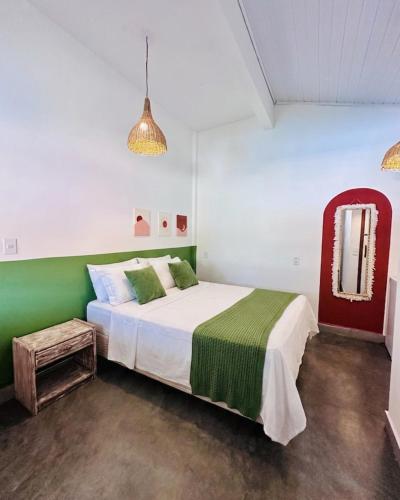 a bedroom with a green and white bed and a mirror at Refugá in Porto Seguro