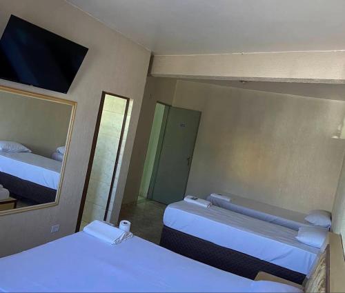 a hotel room with two beds and a mirror at Hotel Matarazzo in São Paulo