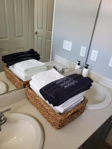 a bathroom with two sinks and two baskets of towels at Family 4BR Home with Spacious Backyard in Coachella