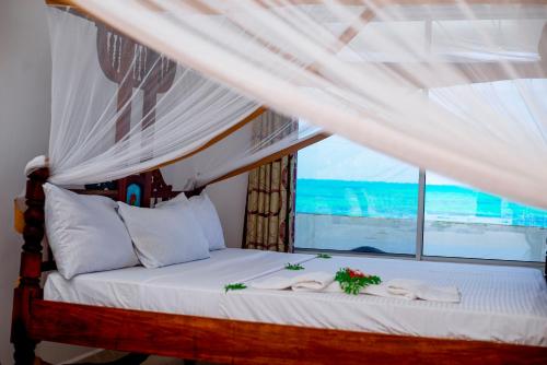 a bedroom with a bed with white sheets and a window at Visitors Inn Zanzibar in Jambiani