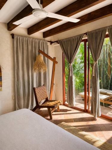 a bedroom with a bed and a chair and a window at Casa Coconut in Puerto Escondido