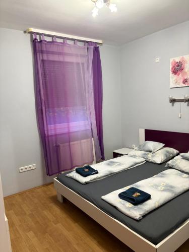 a bedroom with two beds and a purple window at 4 Lurkó Apartman Új in Hajdúszoboszló