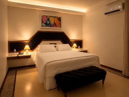 a bedroom with a large white bed and two lamps at Cedro Hotel in Londrina