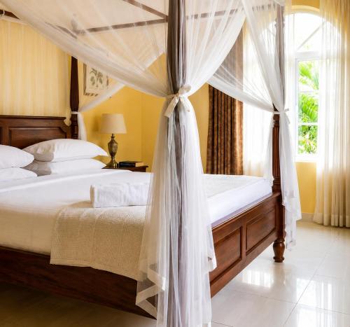 a bedroom with a canopy bed and a window at Mama Maendeleo Resort in Hindi