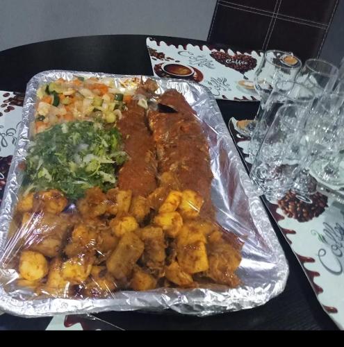 a tray of food with meat and vegetables on a table at Koro Guess House in Lagos