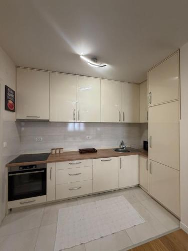 a kitchen with white cabinets and a stove top oven at Apartment Central Point - Podgorica in Podgorica