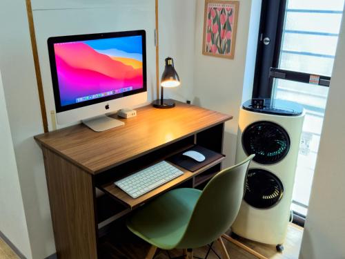 a computer desk with a computer monitor and a chair at Maison Stay Kobe in Kobe