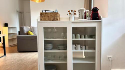 a white cabinet with plates and dishes on it at BorgoLuce Spacious Apt - FREE Parking - Near Airport & Center in Bergamo