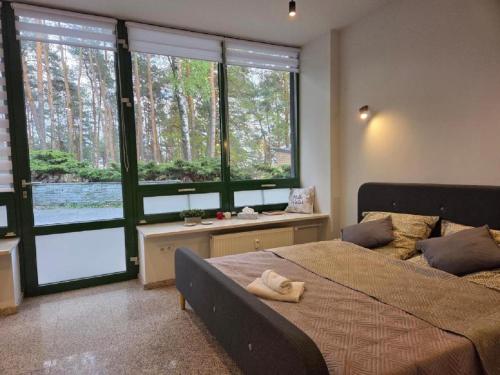 a bedroom with a large bed and large windows at Apartament w Sosnowym SPA in Serock