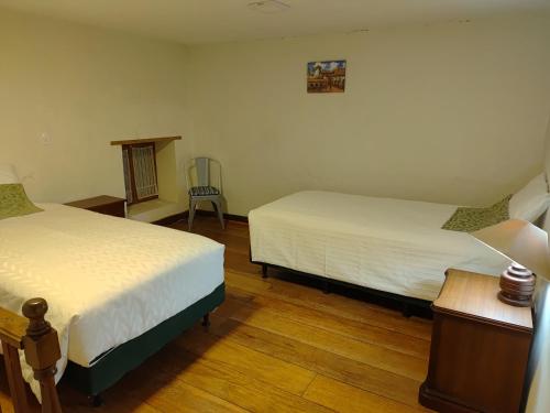 a bedroom with two beds and a table and a chair at Casa Bella Vista Quito Centro Histórico in Quito