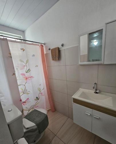 a bathroom with a shower curtain with a toilet and a sink at Residencial Nereu in Bombinhas
