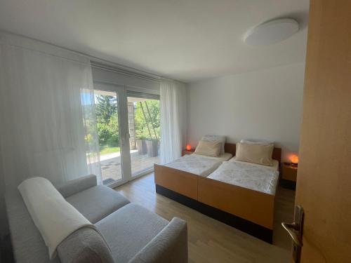 a bedroom with two beds and a couch and a window at Apartma Loško in Cerknica