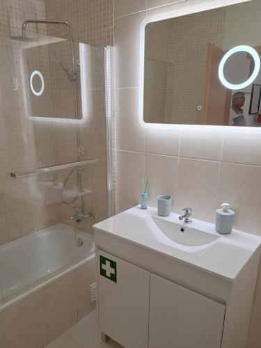a bathroom with a sink and a shower and a mirror at Cristais do Mar in Armação de Pêra