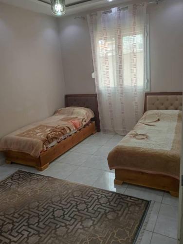 a room with two beds and a window and a rug at Grand joli F3 Draria 7P in Draria