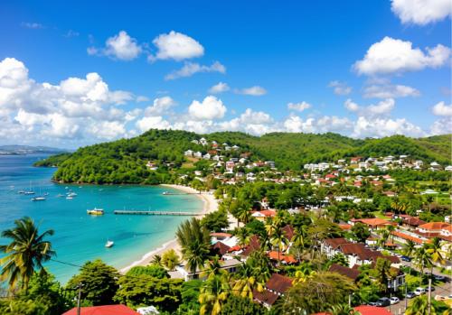 a tropical island with a beach and boats in the water at Le Panoramic in Les Trois-Îlets