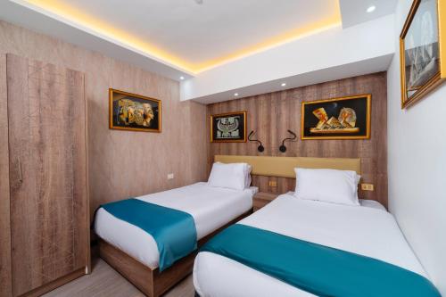 two beds in a small room with paintings on the wall at Aqua Fun Resort in Hurghada