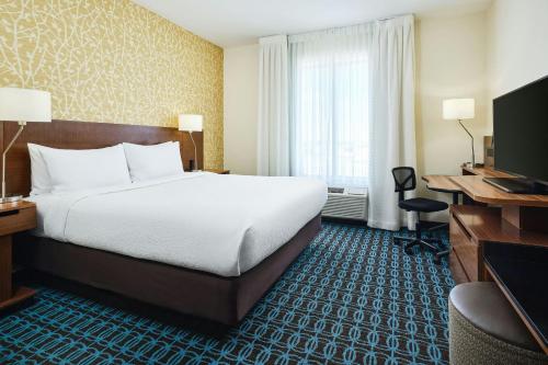 a hotel room with a bed and a desk and a television at Fairfield Inn & Suites by Marriott Sidney in Sidney