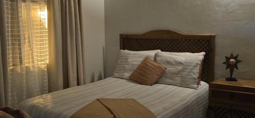 a bedroom with a bed with white sheets and pillows at Casa Vielma in Tapalpa