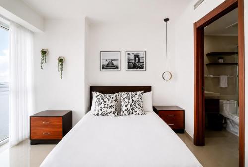 a white bedroom with a bed and a bathroom at THE VIEW AT RIVEFRONT by Bahama Rentals in Guayaquil