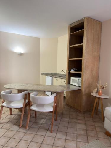 a kitchen with a table and two white chairs at Ingleses Praia Hotel - Com Piscina Aquecida in Florianópolis