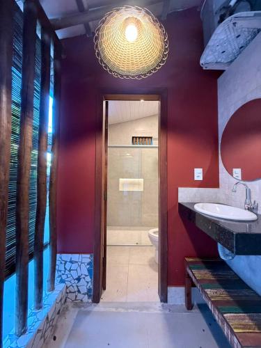 a bathroom with a sink and a red wall at Refugá in Porto Seguro
