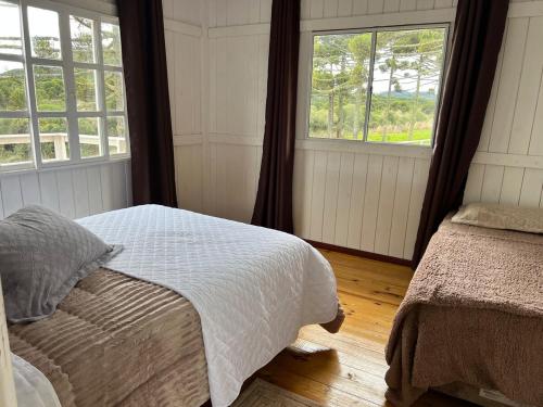 a bedroom with two beds and two windows at Casa de Campo Bella Vista in Urupema