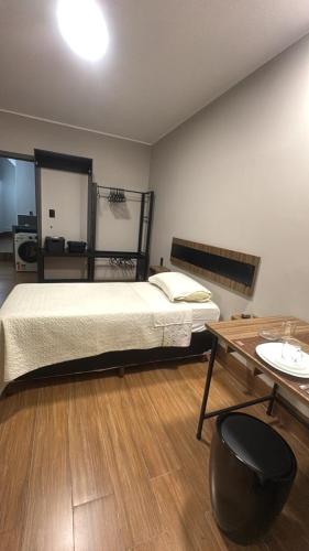 a bedroom with a bed and a desk and a table at Quarto Personalizado Individual aconchegante novo no coração da cidade -Ufla- restaurantes e padaria in Lavras