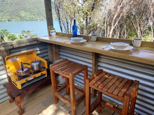 a bar on a porch with a stove and a stool at Endeavour View Eco Cabin in Endeavour Inlet