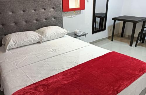 a bedroom with a large bed with a red blanket at Hotel Pasarela in Cali