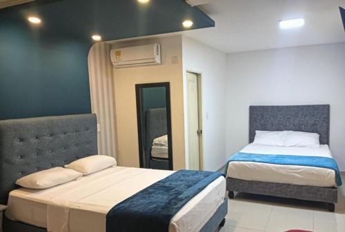 a bedroom with two beds and a mirror at Hotel Pasarela in Cali