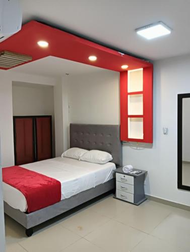 a bedroom with a large bed with a red headboard at Hotel Pasarela in Cali