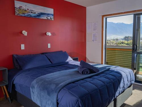 a bedroom with a blue bed with a red wall at Dusky Lodge in Kaikoura