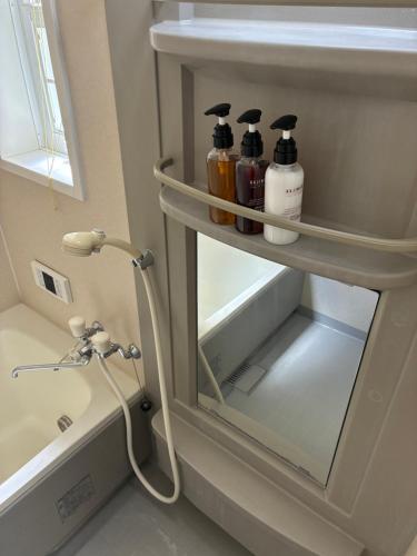 a bathroom with a shelf with three bottles on it at しまなみ海道-愛犬と泊まれる一棟貸し-本格バレルサウナ-ドッグラン-BBQ完備-YOSHIUMi in Imabari