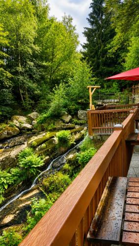 a wooden bridge over a stream with a table and bench at Waldgasthaus & Berghotel Steinerne Renne in Wernigerode